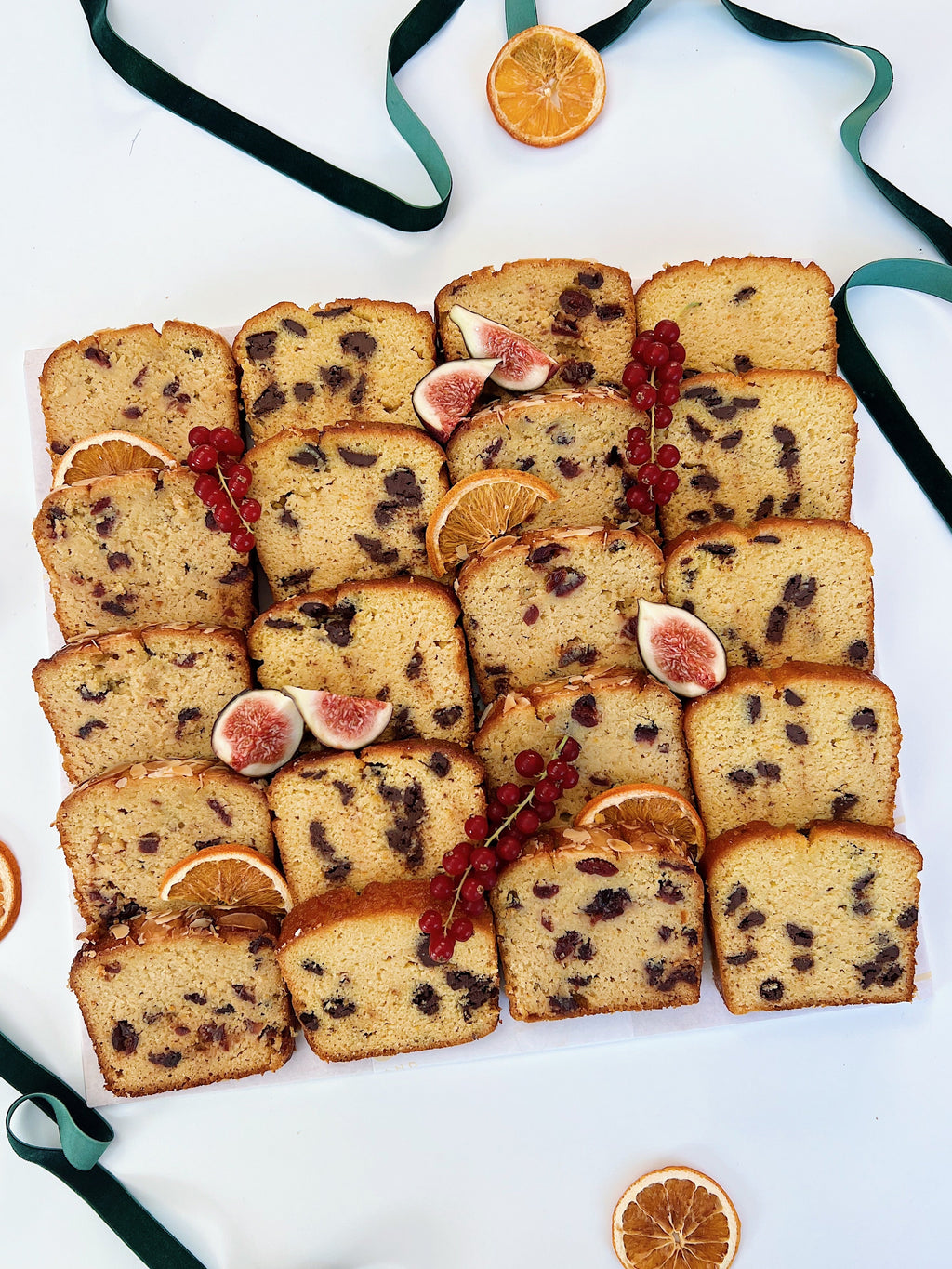 Sliced festive loaf cake platter with figs and oranges on a white background