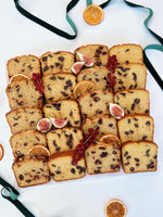 Sliced festive loaf cake platter with figs and oranges on a white background